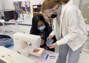 Two students work on sewing projects.